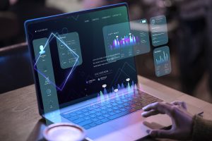Eine Person arbeitet an einem futuristisch wirkenden Laptop mit holografischen Diagrammen und Datenanzeigen – ein Symbol für die digitale Wirtschaft und die zunehmende Bedeutung datenbasierter Entscheidungen in modernen Geschäftsmodellen.