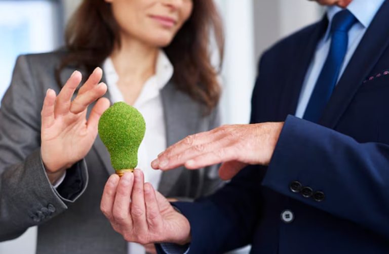 Zwei Geschäftsleute halten gemeinsam eine grüne Glühbirne als Symbol für nachhaltige Investitionen und Green Bonds.