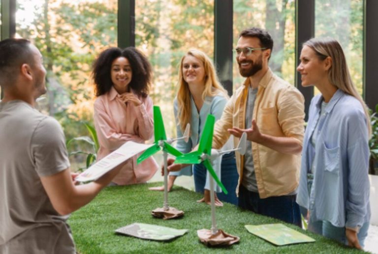 Gruppe junger Unternehmer diskutiert über Windkraftmodelle im Büro, Symbol für Innovation und nachhaltige Ideen von Grüne Startups.