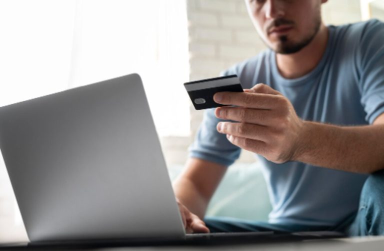 Mann, der mit seinem Laptop eine Online-Zahlung per Kreditkarte tätigt, Symbol für digitale Einkäufe und finanzielle Sicherheit.